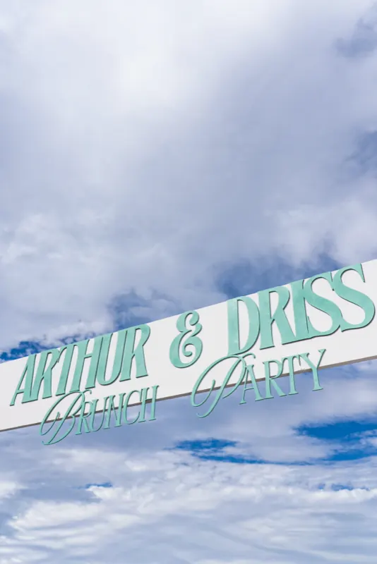 Banderole « Arthur & Driss Brunch Party » sur fond de ciel bleu