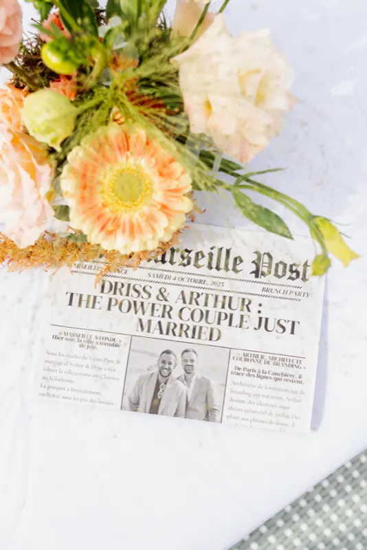 Faux journal « Marseille Post » posé sous un bouquet de gerberas pêche
