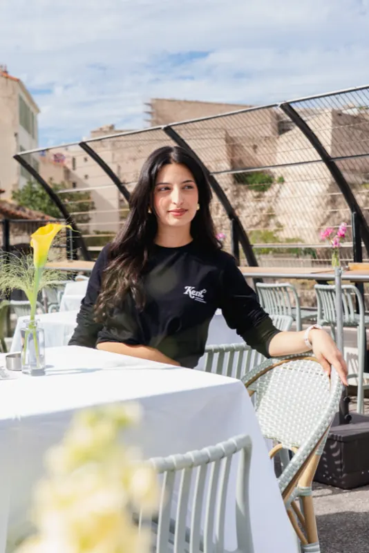 Coordinatrice Kent en sweat brodé du logo, sur la terrasse de l'événement
