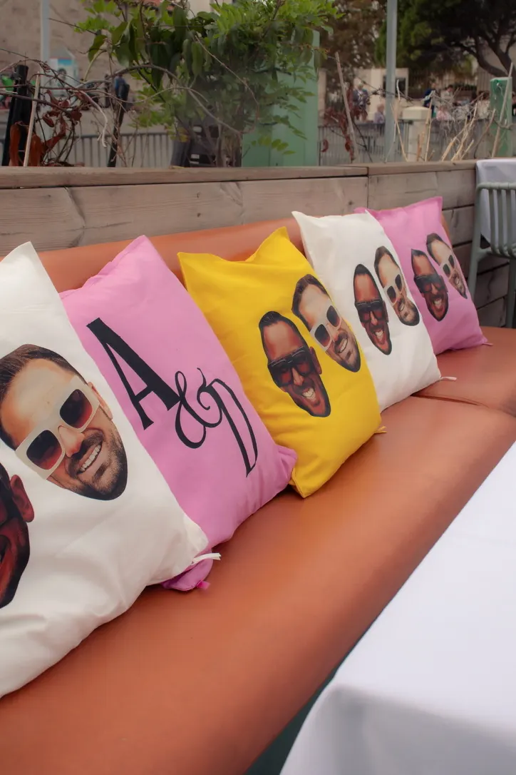 Coussins colorés imprimés des visages et des initiales des invités d'honneur sur une banquette