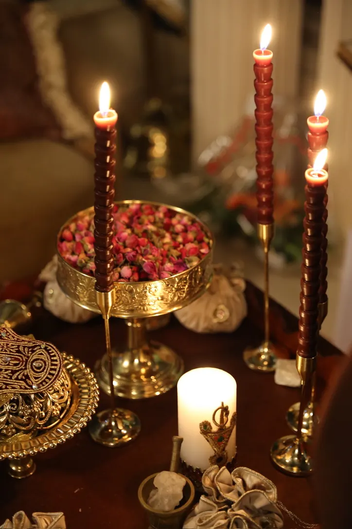 Table de mariage aux bougies bordeaux, coupe dorée de boutons de rose et vaisselle en laiton