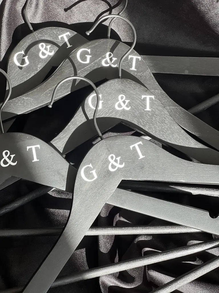 Cintres gris gravés des initiales G et T pour les tenues du cortège