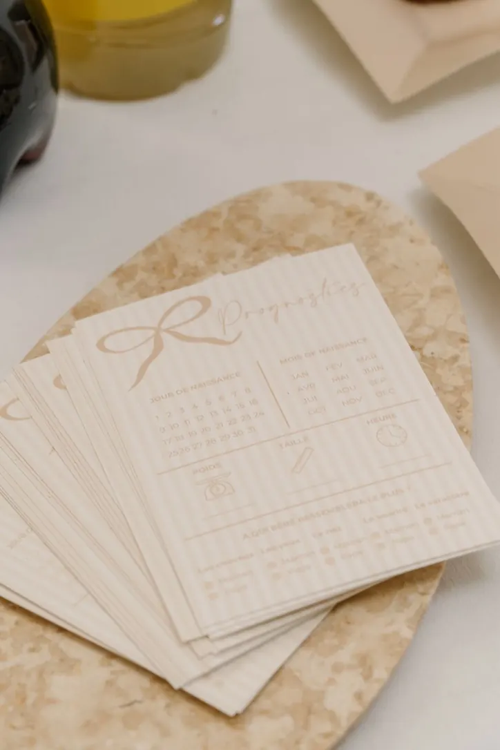 Cartes de jeux de baby shower beige au motif de nœud, posées sur un plateau