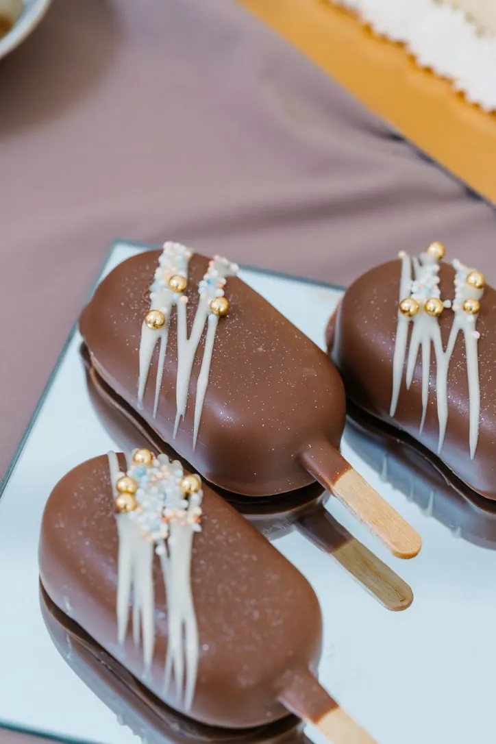 Glaces enrobées de chocolat au lait, décors de chocolat blanc et perles dorées