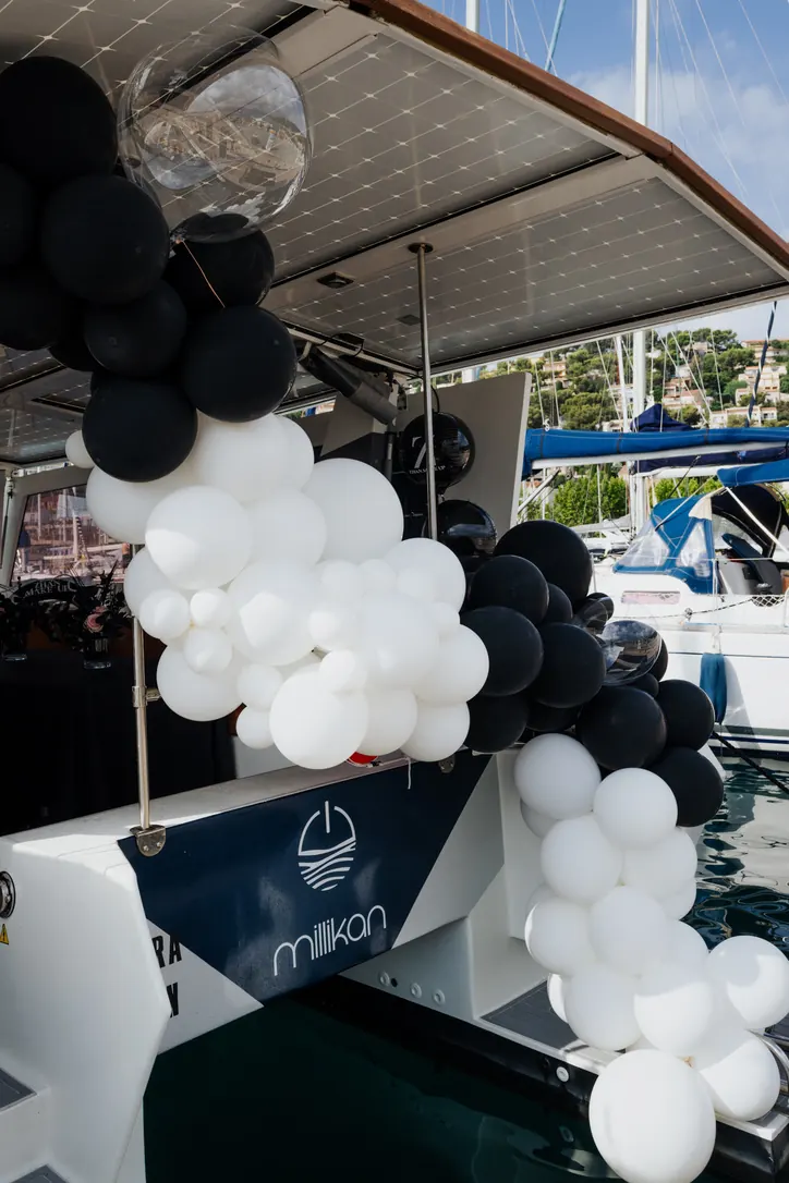 Arche de ballons noirs et blancs à la proue d'un catamaran à quai