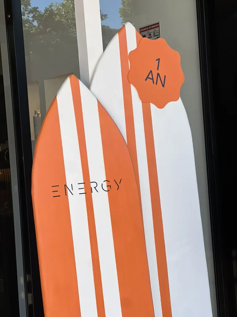 Planches de surf orange et blanc « Energy » et pastille « 1 an » en vitrine