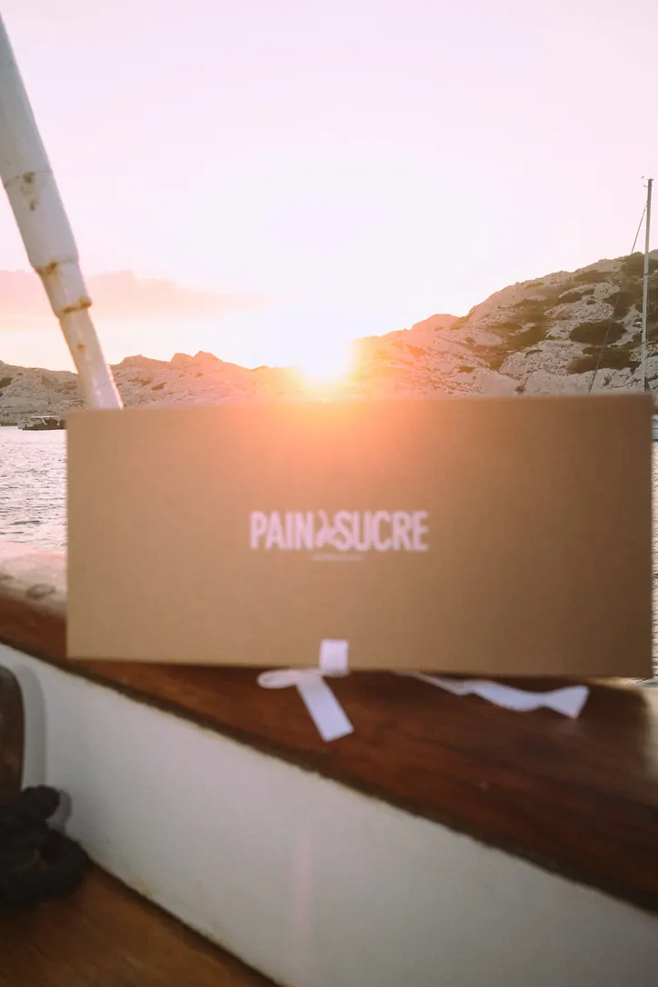 Coffret Pain & Sucre tenu face au coucher de soleil sur les calanques