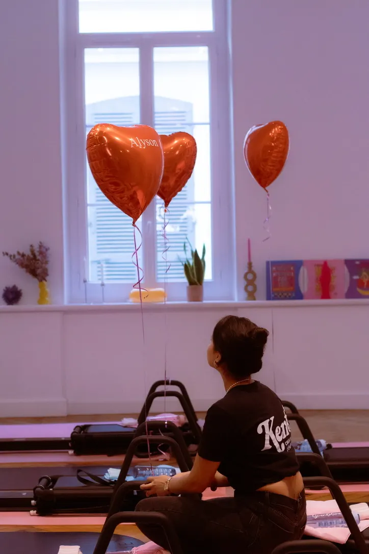 Coordinatrice Kent en t-shirt brodé du logo dans un studio de pilates décoré de ballons cœur